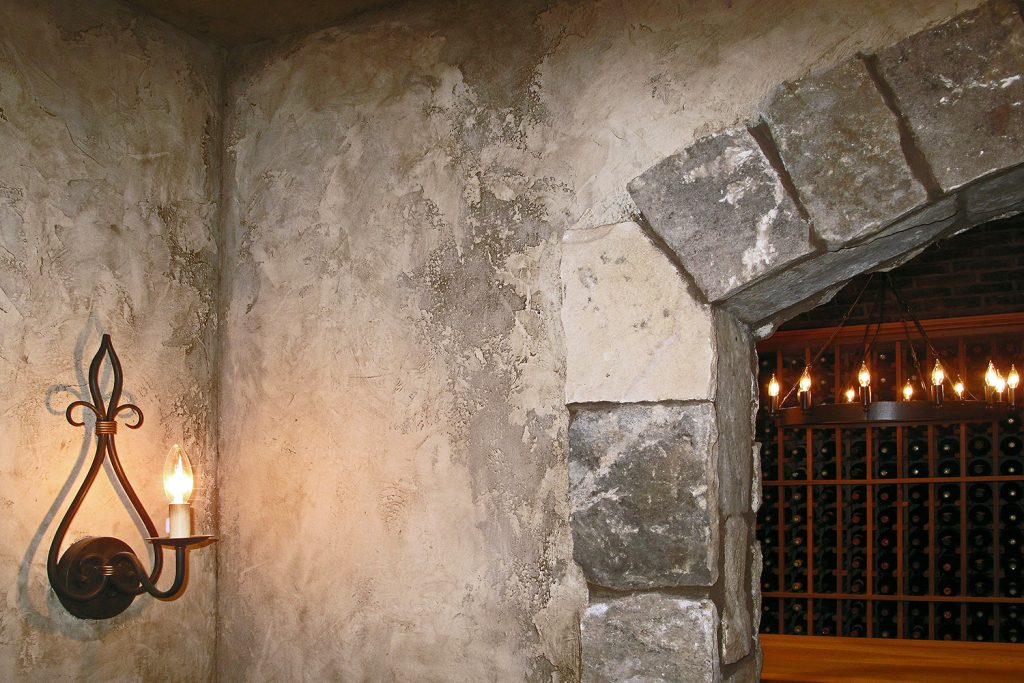 This client was not only serious about their collecting but wanted to actually recreate the experience of being transported to a subterranean wine cellar. The walls are surrounded by the dimensional aged plaster walls that appear to be authentically weathered over centuries. https://kasswilson.com/believable-old-world-wine-cellar-walls/