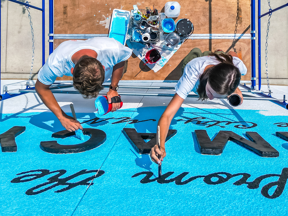 A drone shot above Tony and Brandy Klindworth working on the scaffolding as they painted the lettering of the mural.